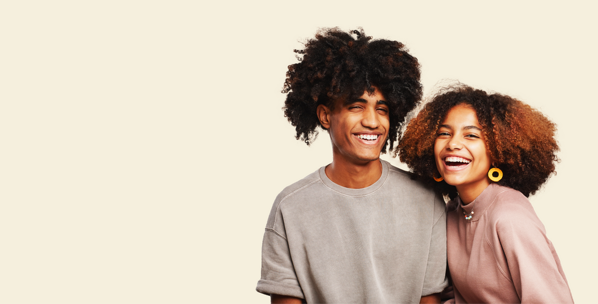 Two people with curly hair happy smiling-faces against a beige background